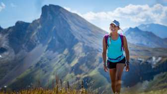 Una giovane donna in abiti estivi fa un'escursione sul Flumserberg durante il tour delle 7 tappe