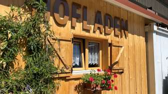 Una capanna di legno con fiori e la scritta "Hofladen" (negozio di fattoria)