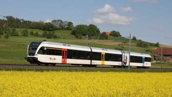 Treno con 3 carrozze che attraversa un paesaggio primaverile in Svizzera