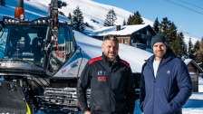 Il pilota del Pistenbully Peter Thut in piedi con il presentatore Manuel Rothmund davanti al Pistenbully sulla neve