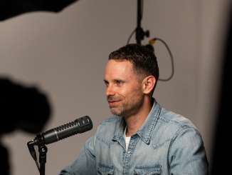 Il presentatore Manuel Rothmund siede davanti al microfono nello studio del podcast